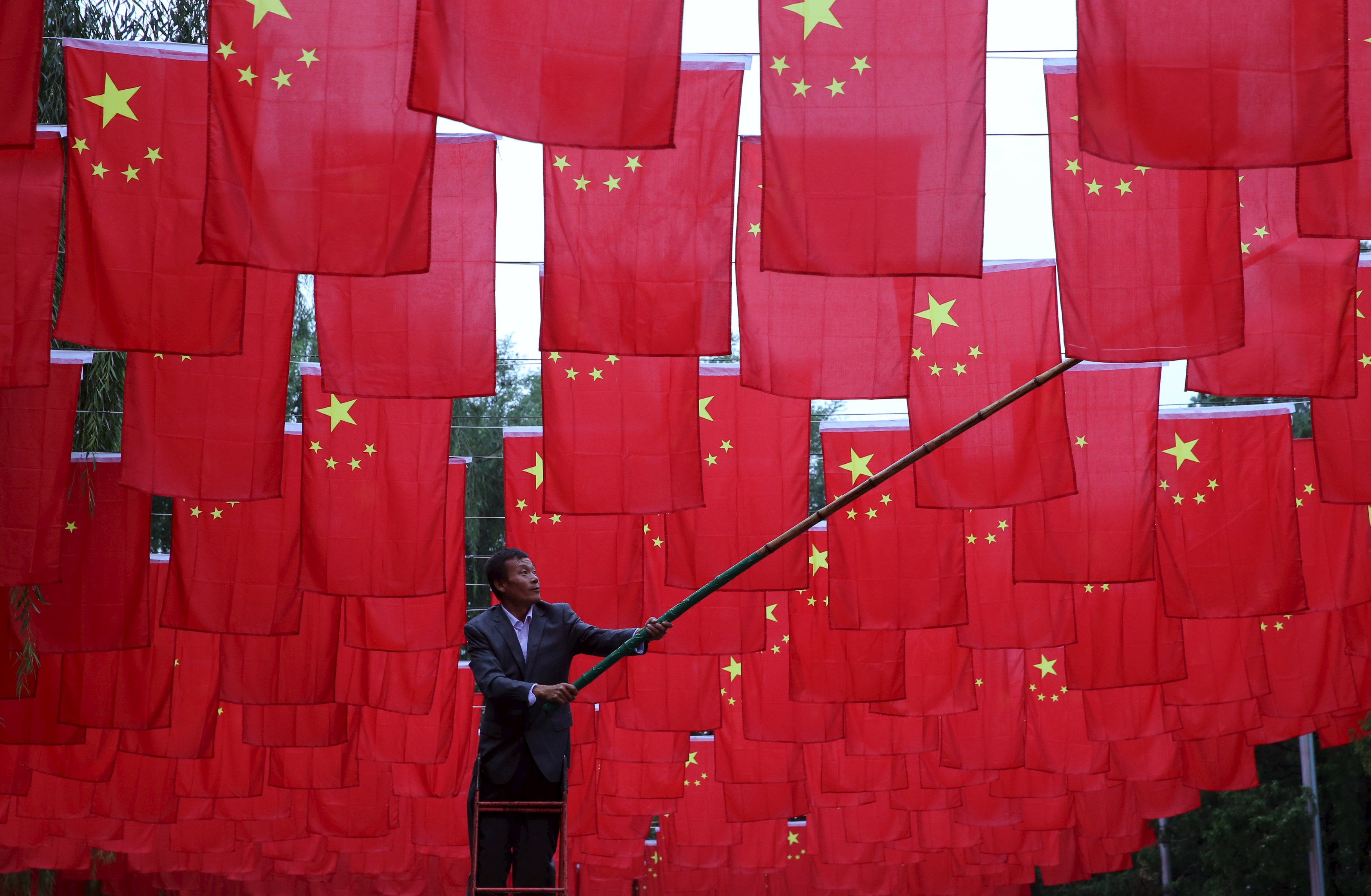 Seorang pria memasang bendera Tiongkok sebagai dekorasi taman, menjelang Hari Nasional Tiongkok di Beijing, Selasa (29/9). ANTARA FOTO/REUTERS/China Daily.