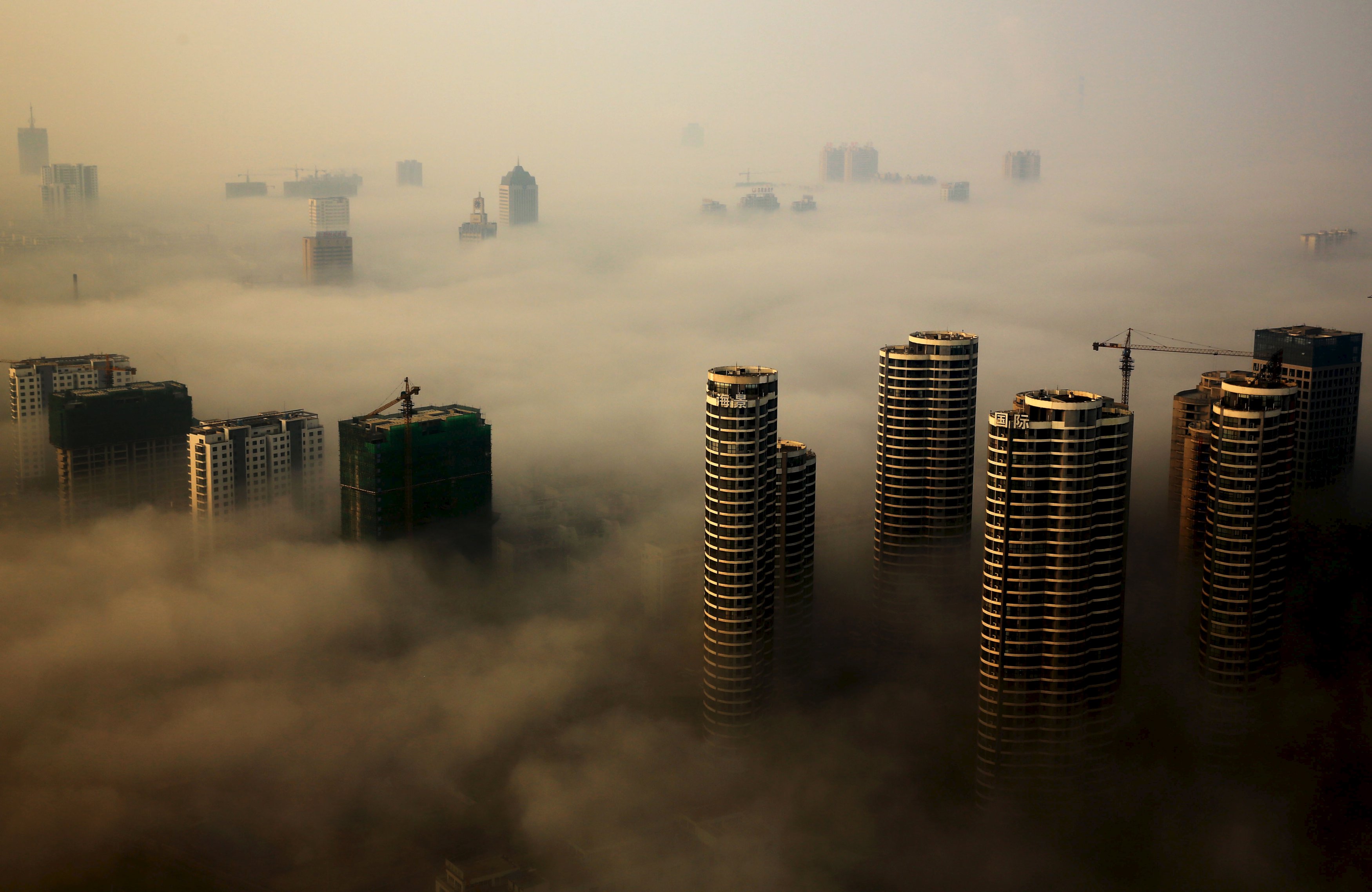 Gedung yang masih dalam konstruksi terlihat di antara kabut saat hari berkabut di Rizhao, Provinsi Shandong, Tiongkok, 18 Oktober 2015. ANTARA FOTO/REUTERS/Stringer.