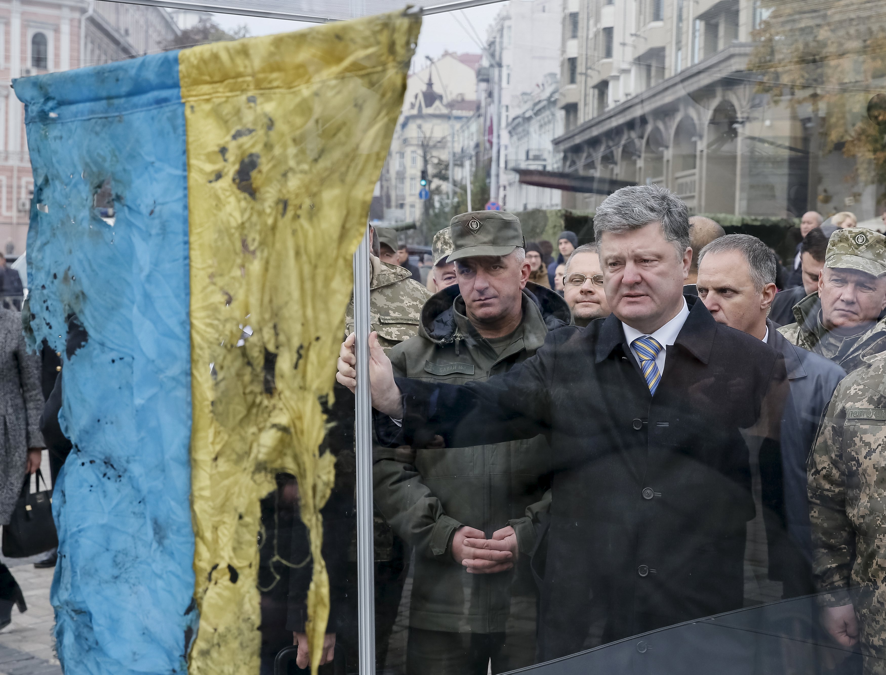 Presiden Ukraina Petro Poroshenko (tengah) melihat bendera Ukraina yang dibawa dari wilayah timur Ukraina dimana konflik militer terjadi, selama kunjungannya di pameran peralatan militer baru di Kiev, Ukraina, 14 Oktober 2015. Ukraina merayakan Hari Pertahanan pada hari Rabu. ANTARA FOTO/REUTERS/Gleb Garanich.