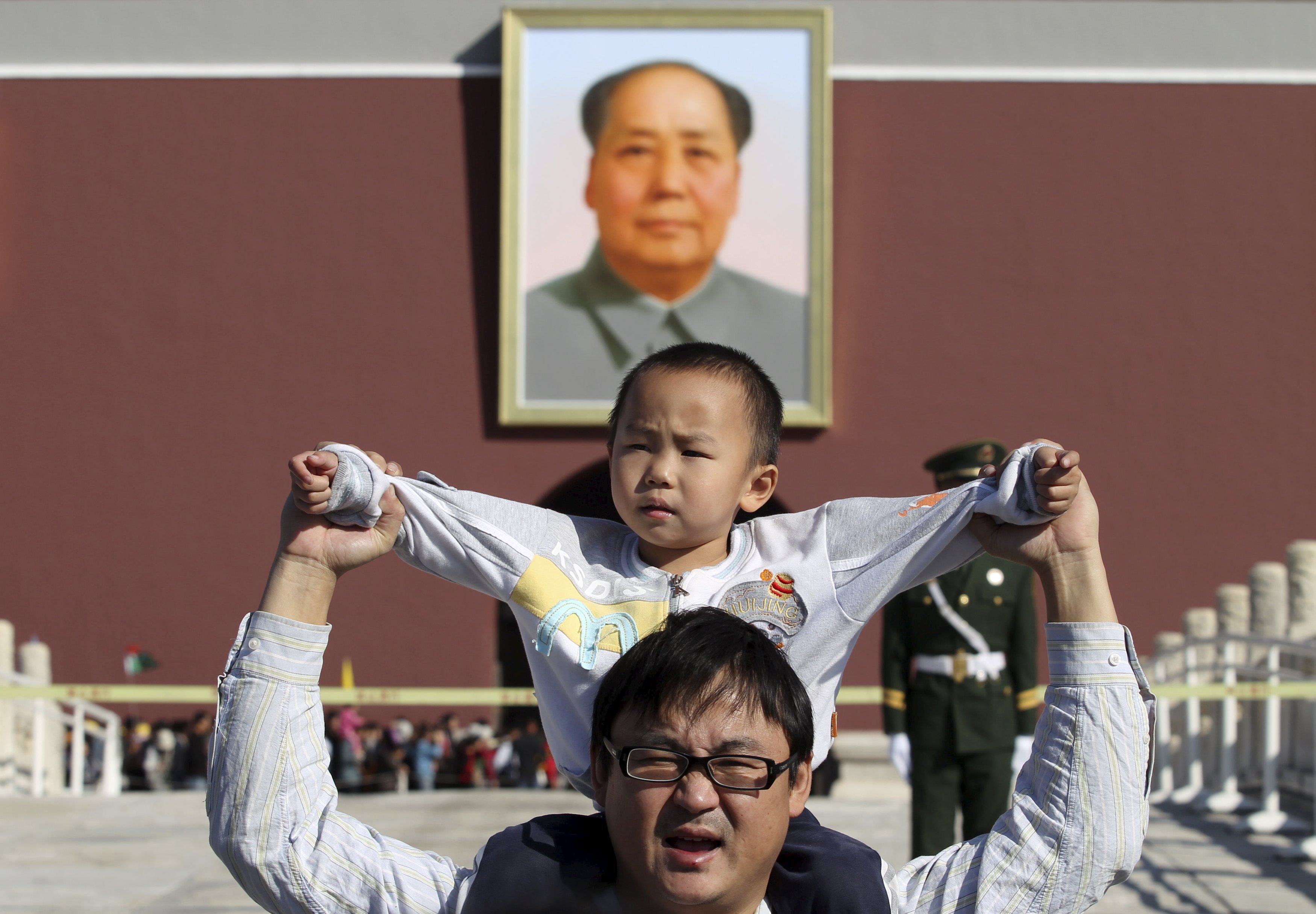 Anak laki-laki duduk di bahu ayahnya saat berpose di depan foto raksasa Mao Zedong di lapangan Tiananmen, Beijing, Tiongkok, 2 Oktober 2011. Tiongkok mengurangi pembatasan keluarga berencana dengan memperbolehkan keluarga memiliki dua anak setelah puluhan tahun menerapkan kebijakan satu anak dengan ketat, menurut Partai Komunis berkuasa pada hari Kamis (29/10), langkah yang ditujukan untuk menambah angka penduduk dalam perkembangan ekonomi. Foto diambil pada tanggal 2 Oktober 2011. REUTERS/Stringer.